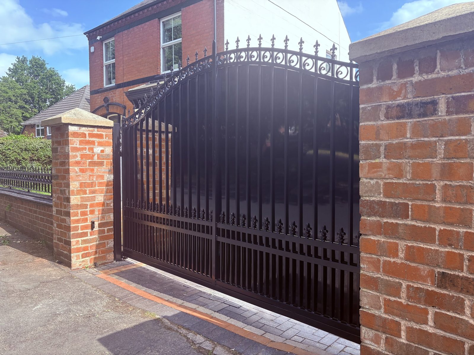 Arched estate gates with cast finials on brick piers